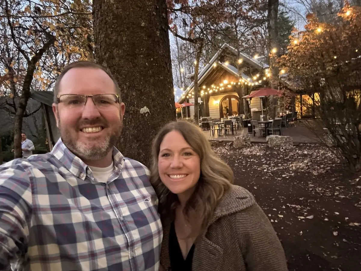Amber and Jake smiling outside a warmly lit restaurant in the Smoky Mountains
